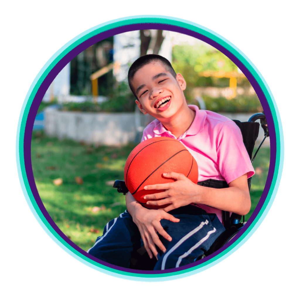 A smiling child in a wheelchair holding a basketball, outdoors in a sunny setting.