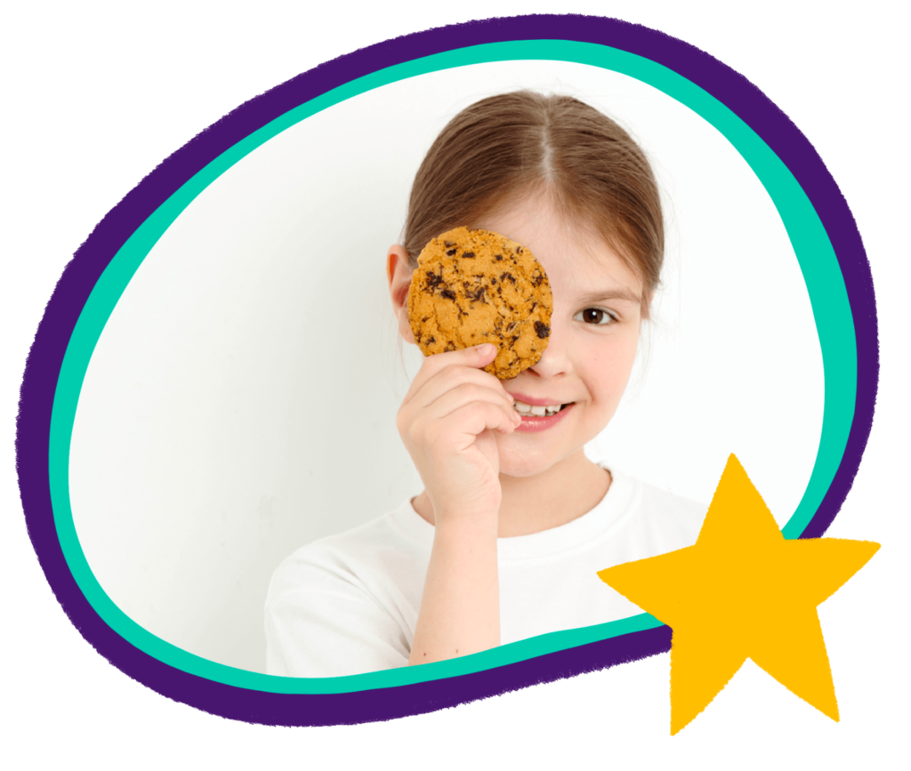 A child holds a cookie in front of her eye, with a yellow star in the corner.
