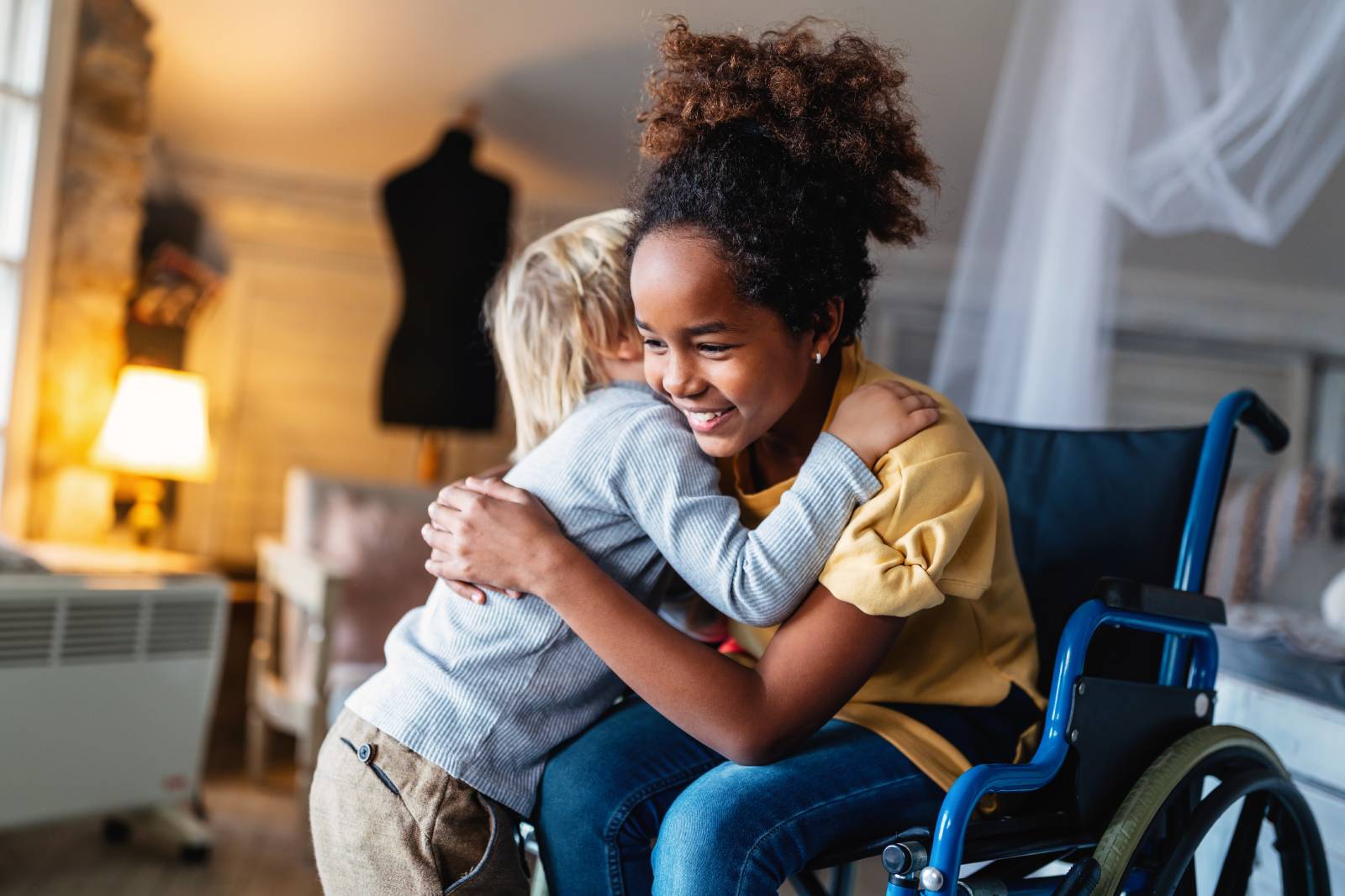 Two children hugging, with one sitting in a wheelchair.