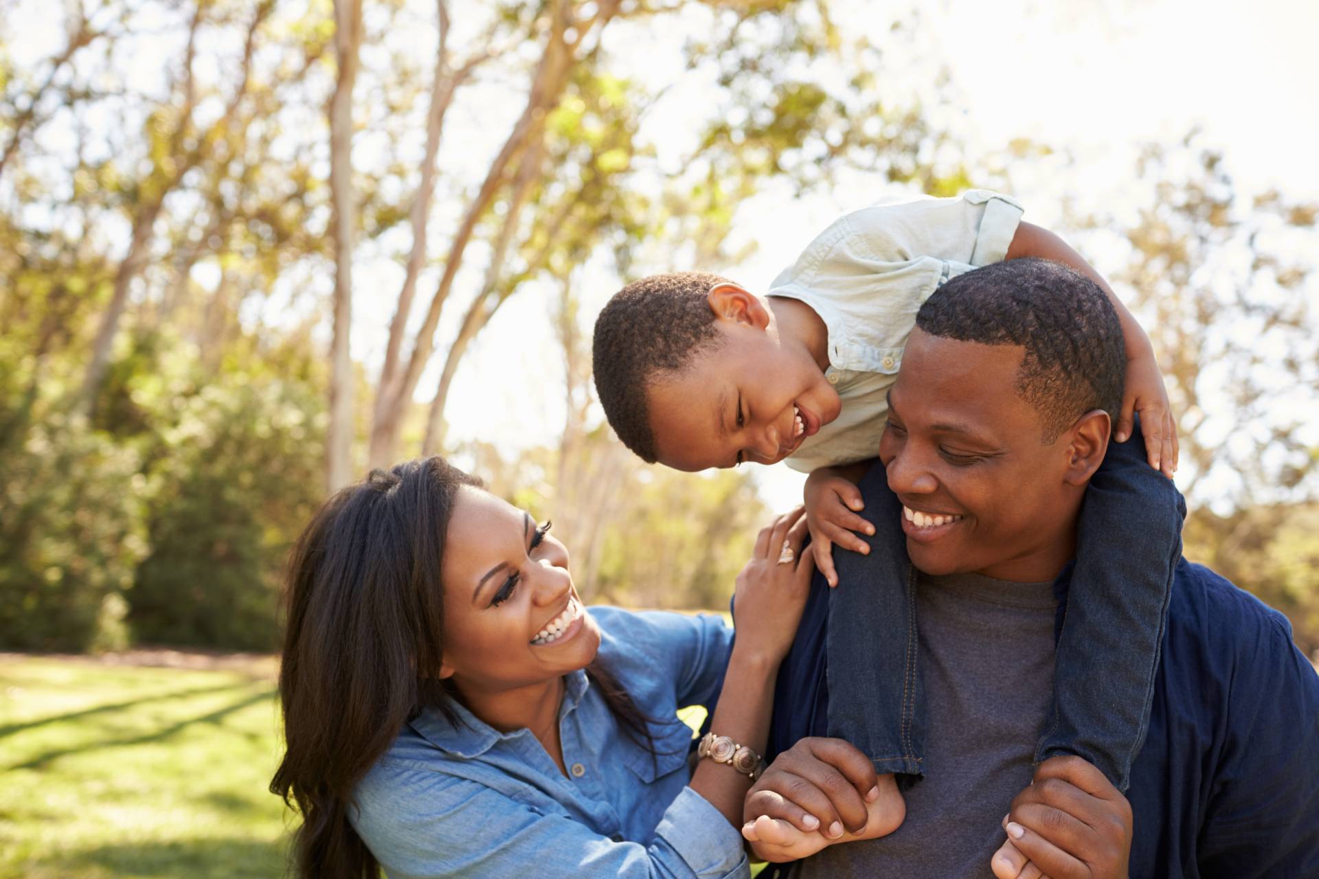 A joyful family moment with two adults and a child sharing a playful time outdoors.