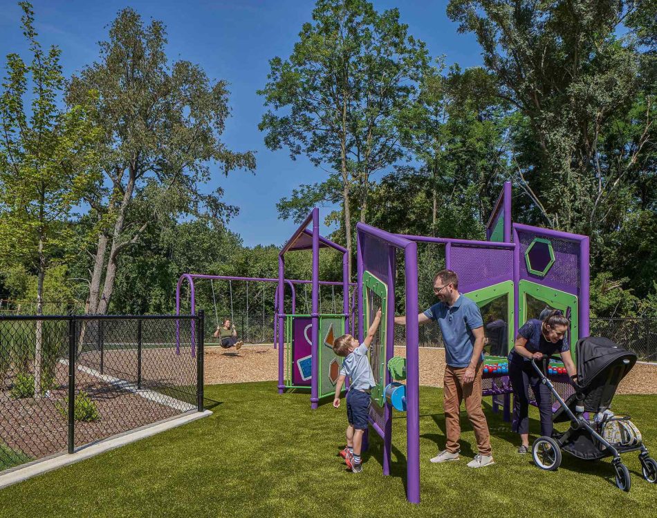 A family enjoys a sunny day at a vibrant playground, interacting with the play structures.