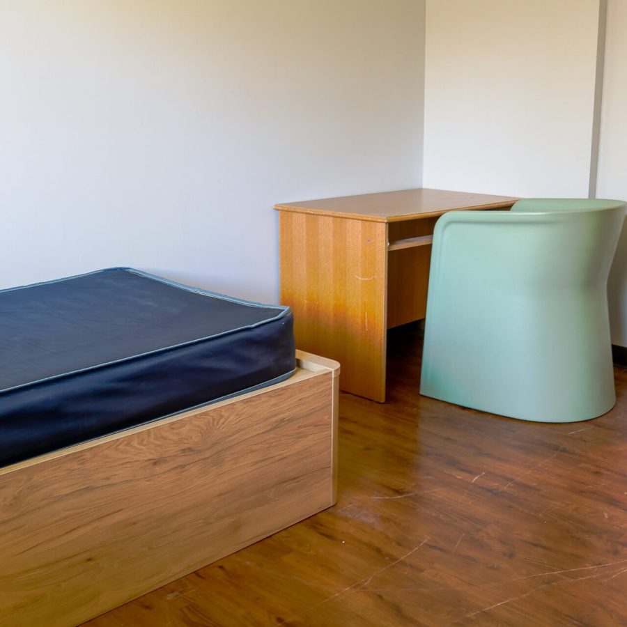 A simple room featuring a bed, desk, and chair with bare essentials, possibly for residential treatment homes for youth.