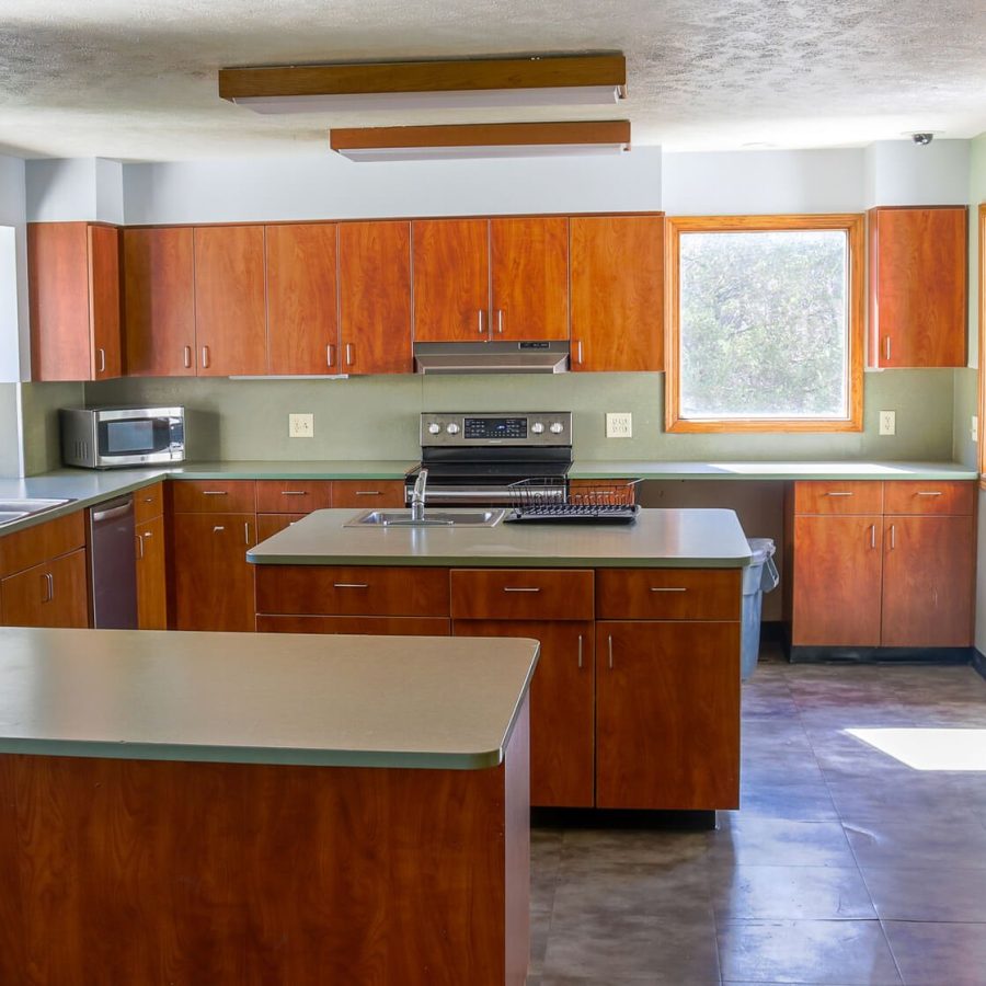 A kitchen with wooden cabinets, a stove, a sink, and a microwave suggests a homely environment.